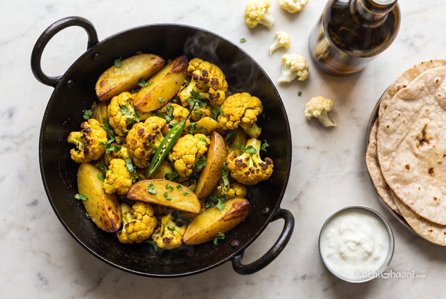 Aloo Gobhi, turmeric-yellow cauliflower florets with dark caramelised edges and thick potato wedges crisped at the