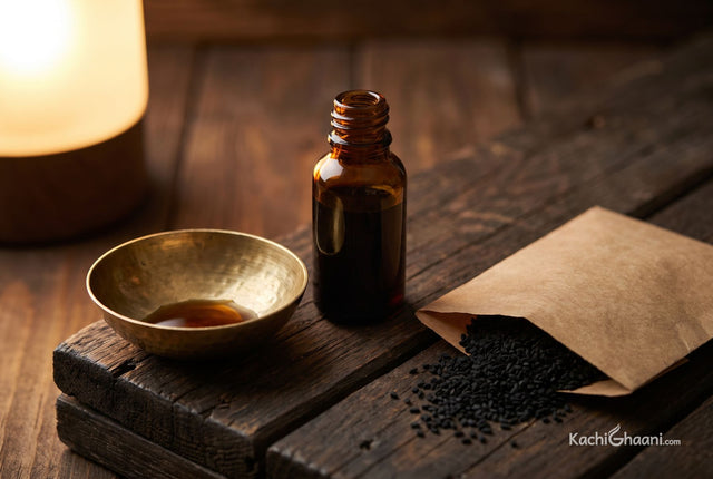 Kalonji oil, a small squat amber glass bottle of near-black kalonji oil with the cap off