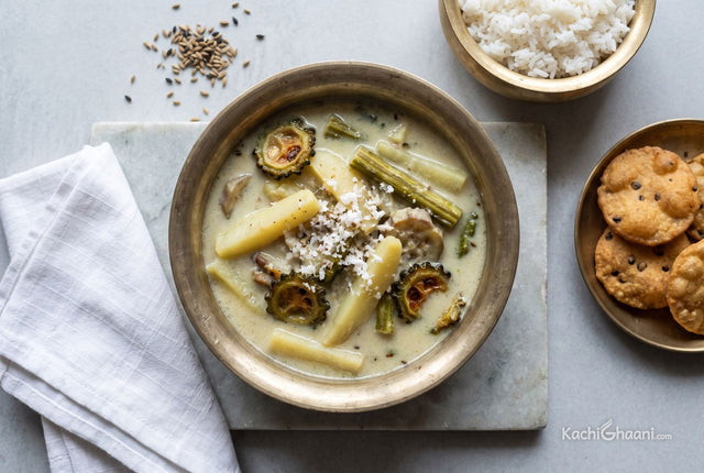 Pale milky shukto with potato, drumstick and bitter gourd in a bell metal bowl