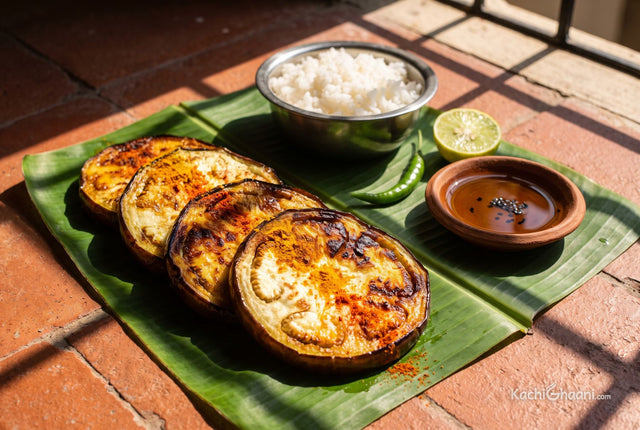 Thick fried brinjal rounds with crisp caramel edges, served on a banana leaf with rice