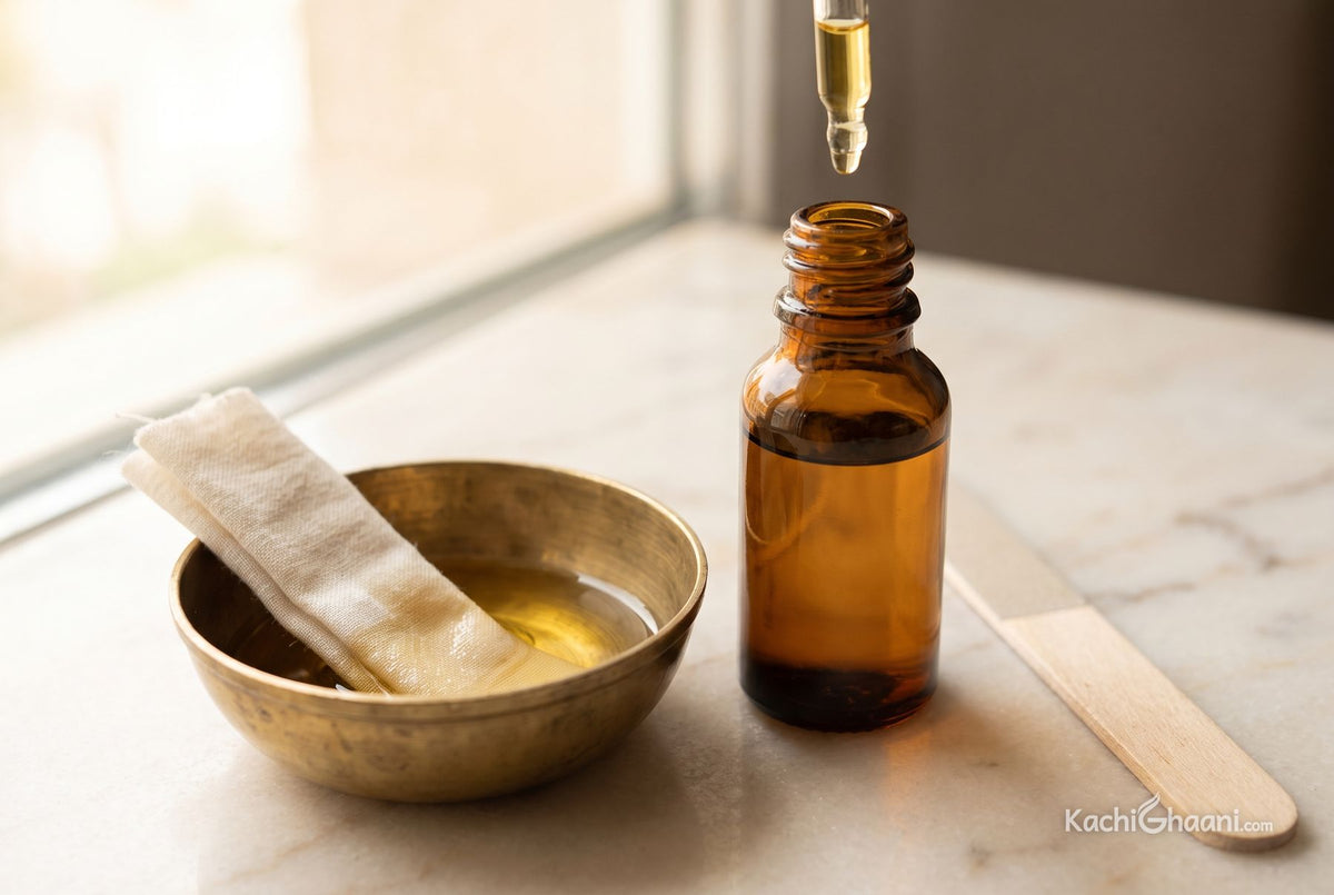 Castor oil for nails and cuticles, a small amber glass dropper bottle of thick castor oil with a single slow golden drop hanging at the tip