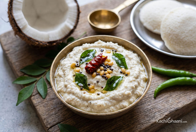 White coconut chutney in a bronze bowl under a mustard seed and curry leaf tempering