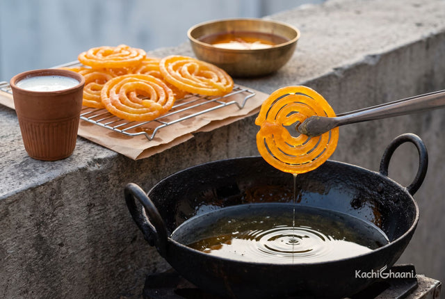 Jalebi, bright saffron-orange coiled spirals with a glassy syrup coating