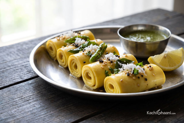 Khandvi, a row of pale yellow silky besan rolls the thickness of a pencil, tightly coiled and glossy