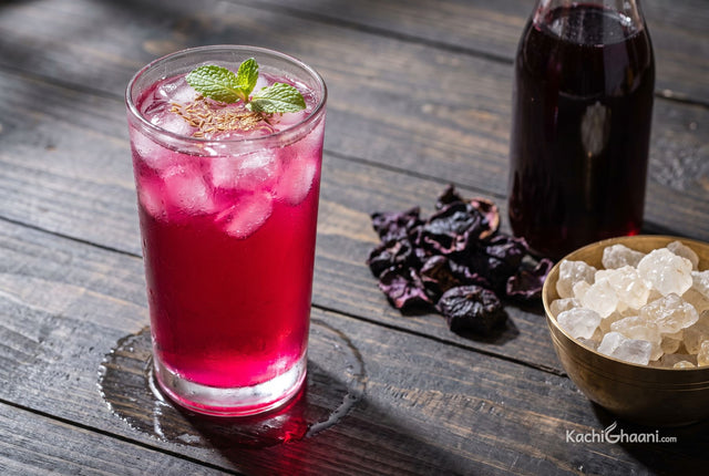 Kokum Sharbat, a tall glass of kokum sharbat on a dark weathered wooden table