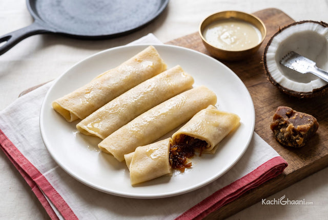 Soft rolled crepes filled with coconut and jaggery, arranged warm on a plate