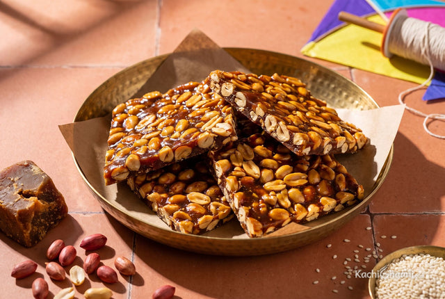 Glassy amber jaggery peanut chikki snapped into rough pieces on a brass plate