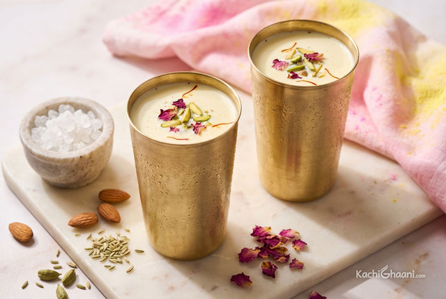 Chilled spiced thandai in brass tumblers topped with pistachios and saffron strands